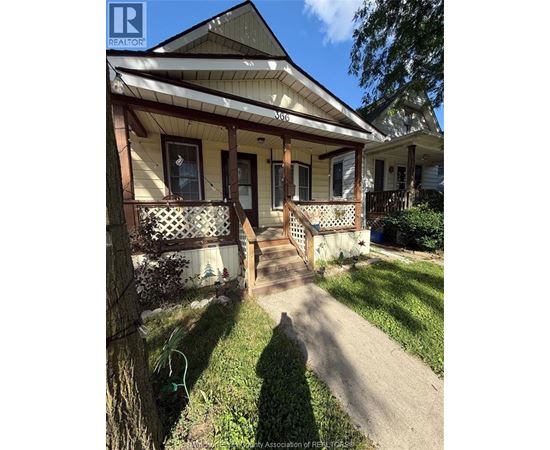 A house with a porch and a tree in front of it.