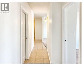 A hallway with tiled flooring and white walls.