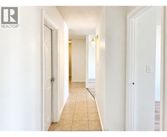 A hallway with tiled flooring and white walls.