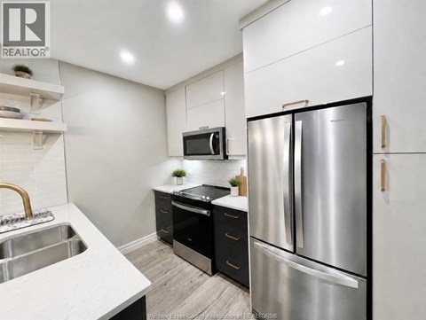 A modern kitchen with a stainless steel refrigerator and a white countertop.