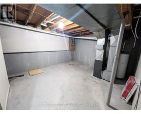 A spacious, unfinished basement with a concrete floor and walls, and a few items scattered around.