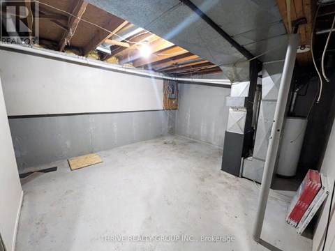 A spacious, unfinished basement with a concrete floor and walls, and a few items scattered around.
