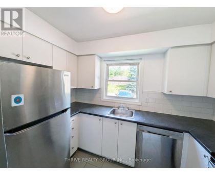 A kitchen with a stainless steel refrigerator and a window.