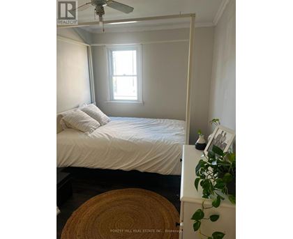 A bedroom with a bed, a ceiling fan, and a window.