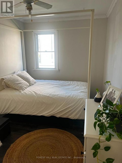 A bedroom with a bed, a ceiling fan, and a window.