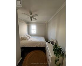 A bedroom with a bed, a ceiling fan, and a window.