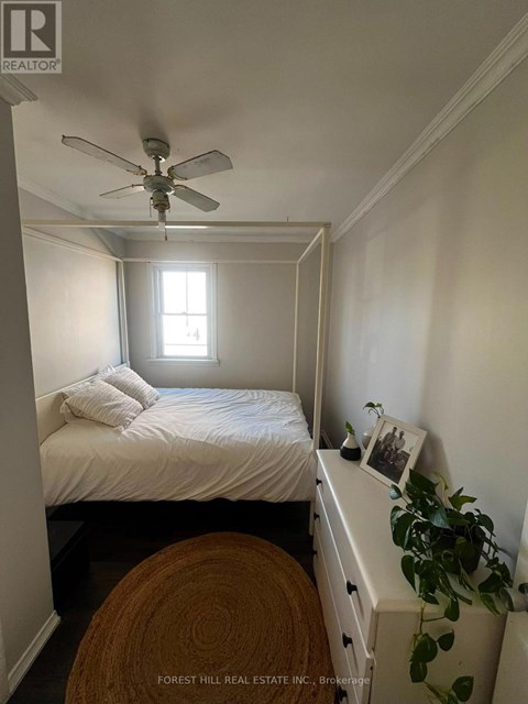 A bedroom with a bed, a ceiling fan, and a window.