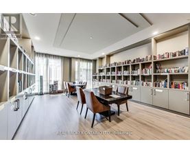 A room with a long table and chairs with a bookshelf on the side.