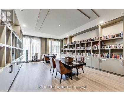 A room with a long table and chairs with a bookshelf on the side.