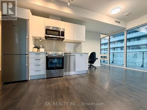 A modern kitchen with stainless steel appliances and a black chair.