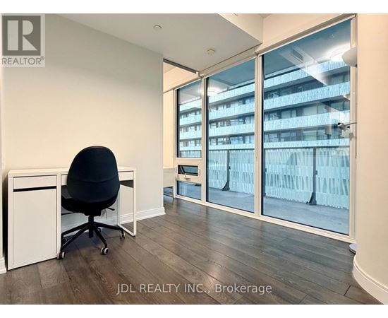 A room with a black chair and a desk with a white cabinet.