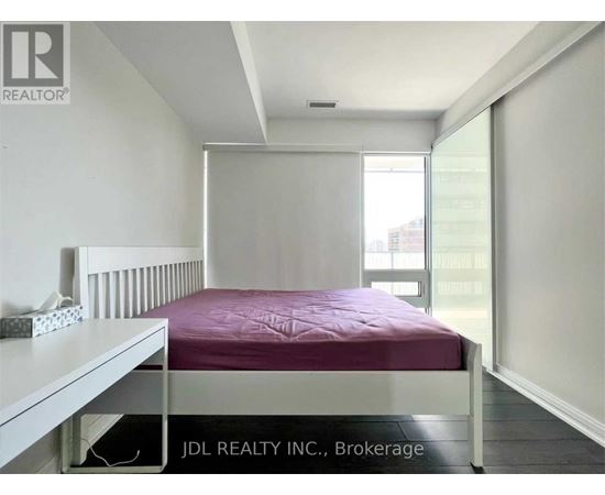 A bedroom with a bed, nightstand, and window.