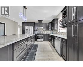 A modern kitchen with black cabinets and a marble countertop.