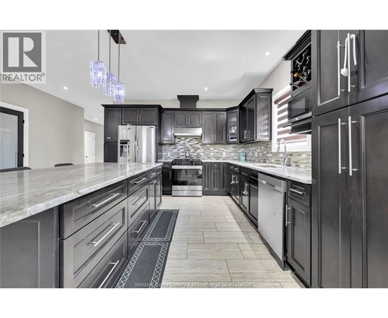 A modern kitchen with black cabinets and a marble countertop.