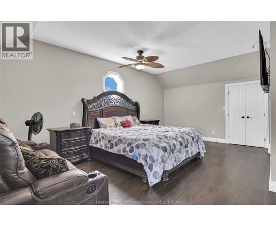 A bedroom with a large bed and a ceiling fan.