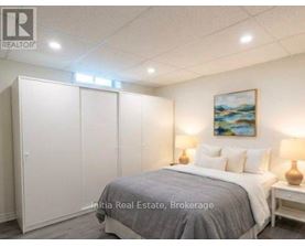 A bedroom with a bed, two lamps, and a painting on the wall.