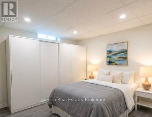 A bedroom with a bed, two lamps, and a painting on the wall.
