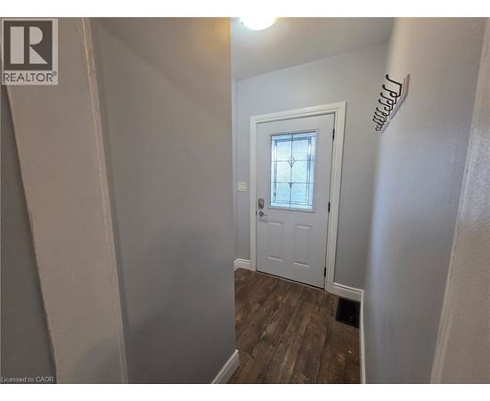 A white door with a glass window is in a room with wooden flooring.