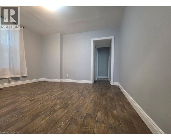 A room with wooden flooring and a doorway leading to another room.