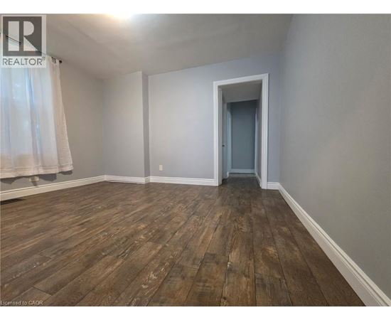 A room with wooden flooring and a doorway leading to another room.