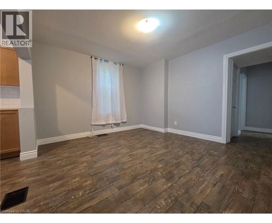 A room with wooden flooring and a window with curtains.