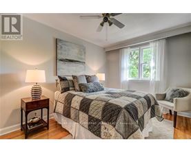 A bedroom with a bed, a ceiling fan, and a window.