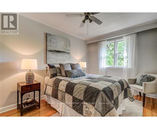 A bedroom with a bed, a ceiling fan, and a window.