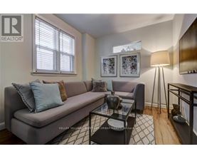 A living room with a grey couch, a glass coffee table, and a lamp.