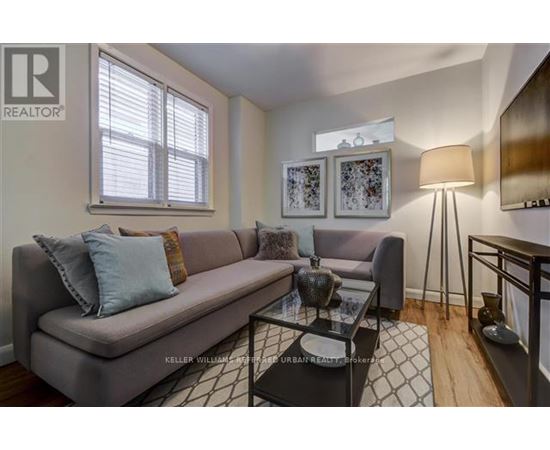 A living room with a grey couch, a glass coffee table, and a lamp.