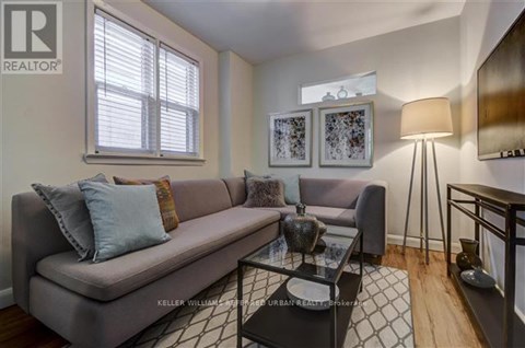A living room with a grey couch, a glass coffee table, and a lamp.