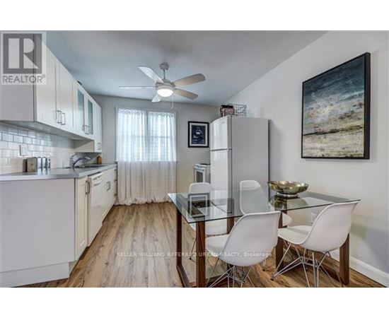 A kitchen with a glass table and white chairs.