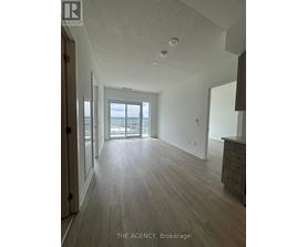 A spacious room with wooden flooring and a view of the outside through a large window.