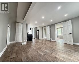 A spacious room with wooden flooring and white walls.