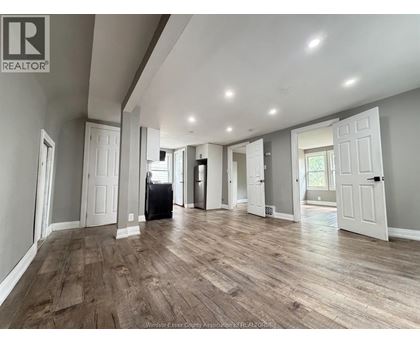 A spacious room with wooden flooring and white walls.