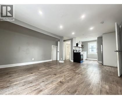 A spacious room with wooden flooring and white walls.