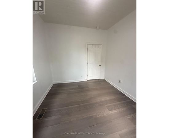 A room with wooden flooring and a white door.