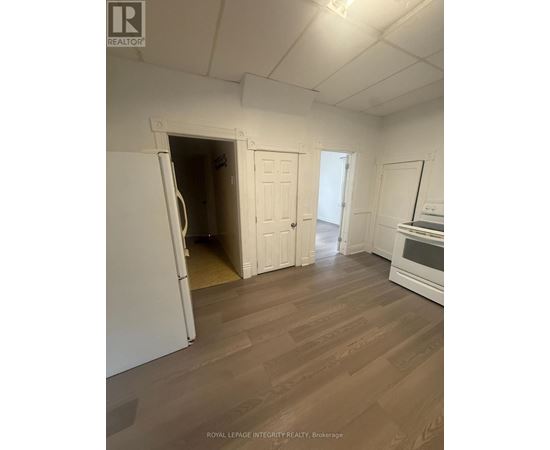 A white refrigerator is in a kitchen with wood flooring.