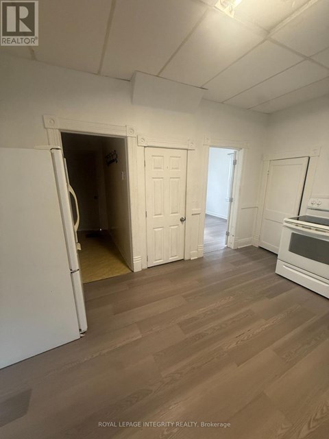 A white refrigerator is in a kitchen with wood flooring.