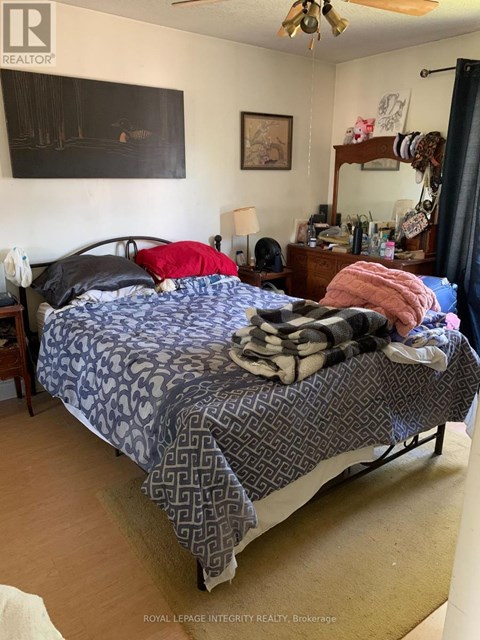 A bedroom with a bed, nightstand, and a painting on the wall.