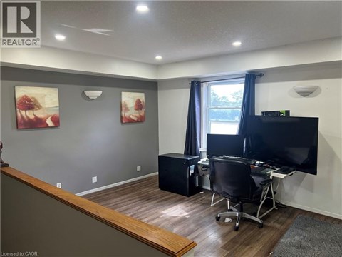 A room with a desk, chair, and television.