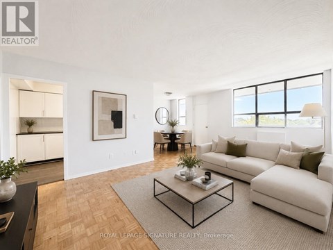 A living room with a white couch, a coffee table, and a large window.