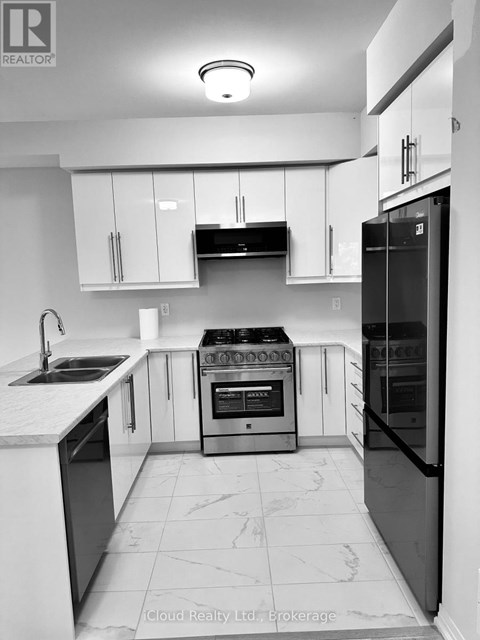 A black and white photo of a modern kitchen with a refrigerator on the right.
