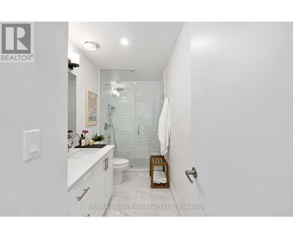 A white bathroom with a glass shower stall and a white toilet.