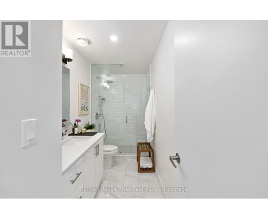 A white bathroom with a glass shower stall and a white toilet.