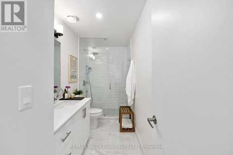 A white bathroom with a glass shower stall and a white toilet.