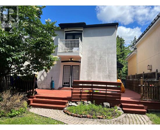 A small house with a balcony and a red staircase leading to the front door.