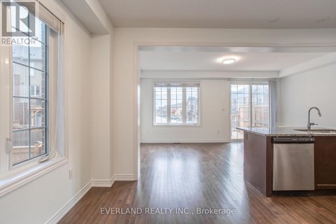A spacious kitchen with wood floors and a large window.