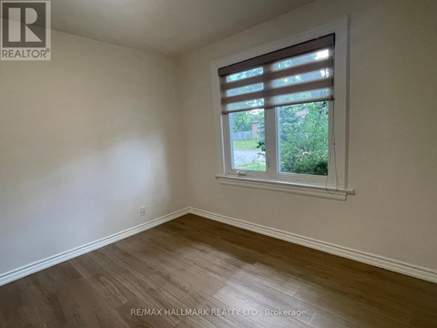 A room with a window and wooden flooring.