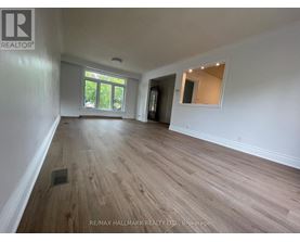 A spacious room with wooden flooring and white walls.