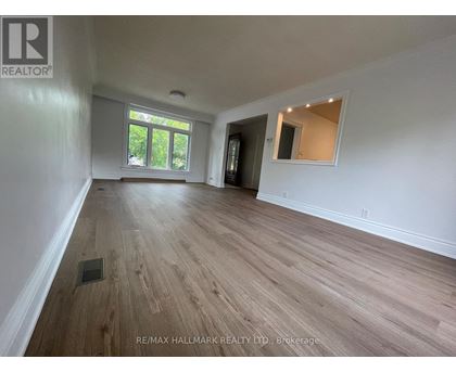 A spacious room with wooden flooring and white walls.